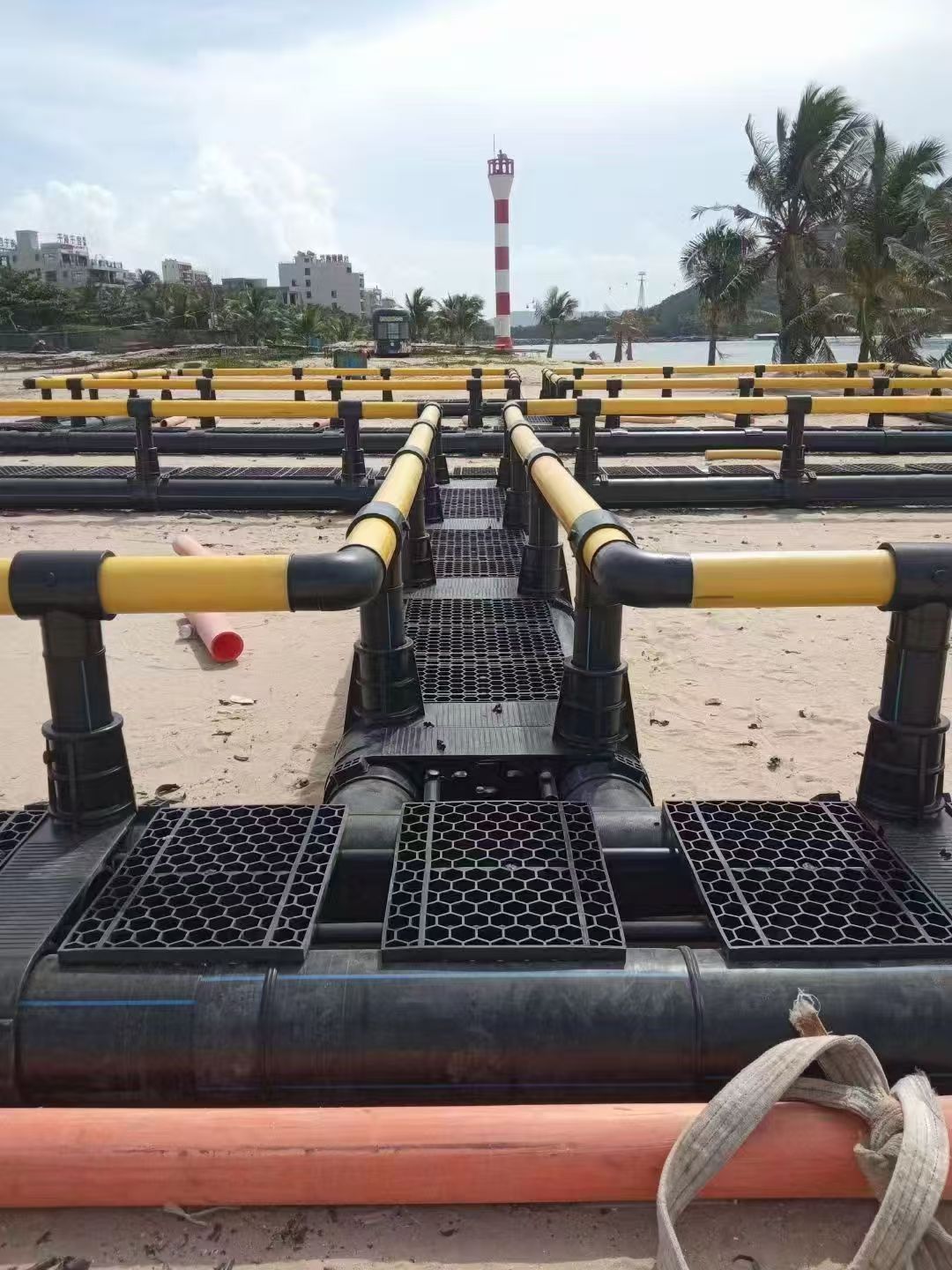 HDPE offshore fish cage structure during shoreline assembly for an aquaculture project